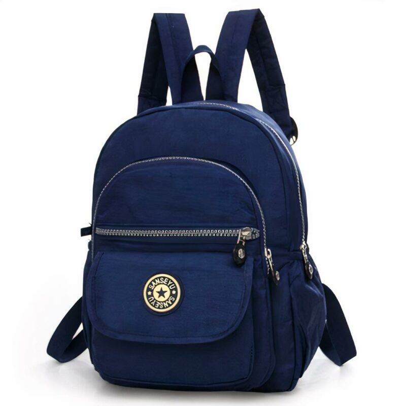Mini sac à dos pour femme étanche de couleur unie bleu marine. Le sac à dos a quatre poches de tailles différentes. Une avec un velcro et 3 avec des zips. Sur la poche avec le velcro, il y a le logo du sac. Le sac a une hanse pour le tenir sur un crochet et deux hanses pour pouvoir le porter sur le dos.