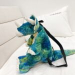 Sac à dos original dinosaure 3D vert avec un fond un lit blanc