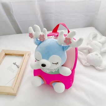 Sac à dos d'école en peluche pour enfant rose dans un lit blanc et une peluche blanche sur le côté