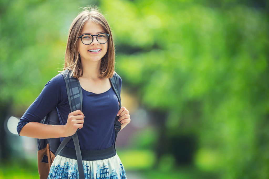 Fille avec un sac à dos sort du collège