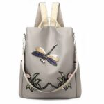 Sac à dos brodé motif fleur et papillon pour femme beige et gris avec un fond blanc