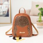 Mini sac à dos à paillette pour fille marron avec un fond une table blanche, un canapé beige et un cadre