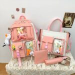 Sac à dos en tissu Oxford quatre pièces avec porte-clés peluche rose avec un fond une table avec d'autres objets