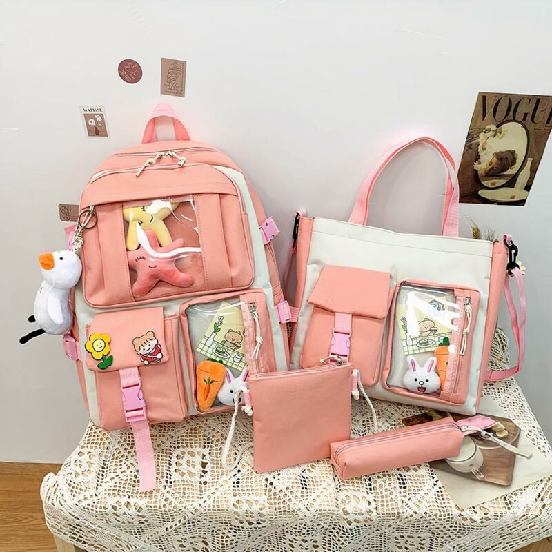 Sac à dos en tissu Oxford quatre pièces avec porte-clés peluche rose avec un fond une table avec d'autres objets