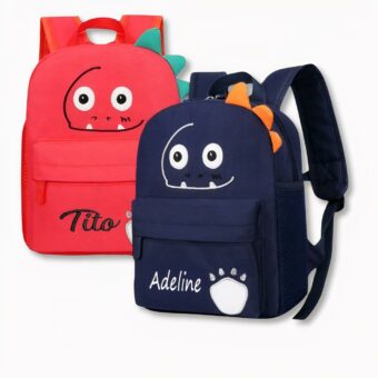 2 sacs à dos pour enfants, l'un rouge et l'autre bleu foncé avec des visages de dinosaures souriants et personnalisés au nom de Tito et Adeline, sur fond gris clair