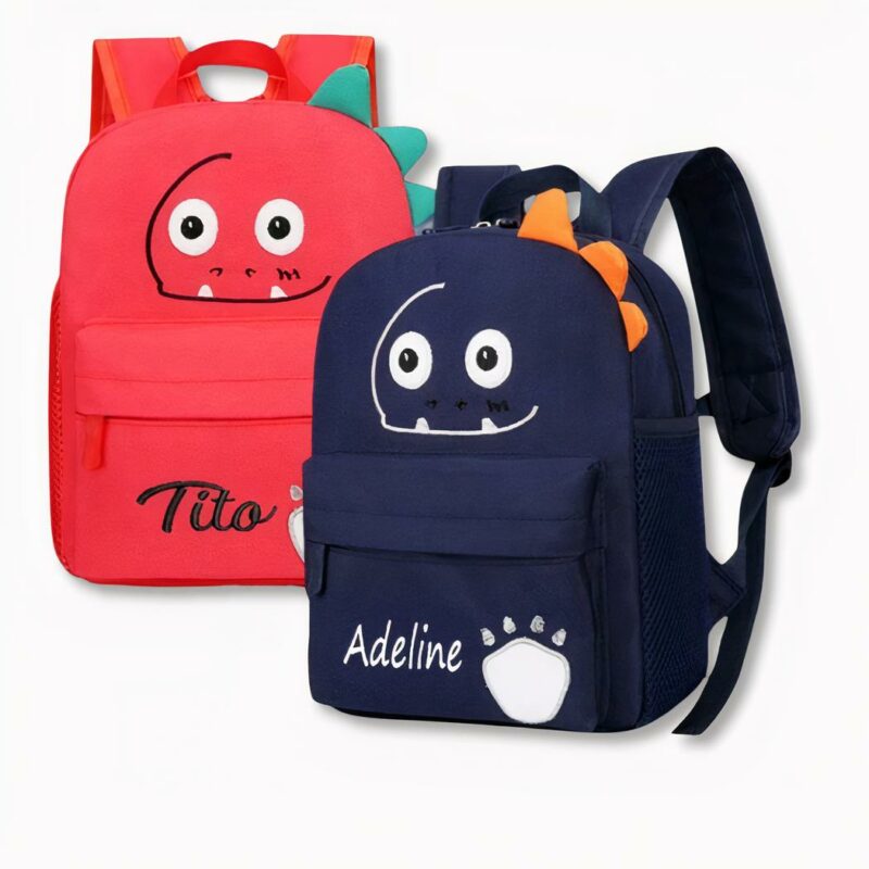 2 sacs à dos pour enfants, l'un rouge et l'autre bleu foncé avec des visages de dinosaures souriants et personnalisés au nom de Tito et Adeline, sur fond gris clair