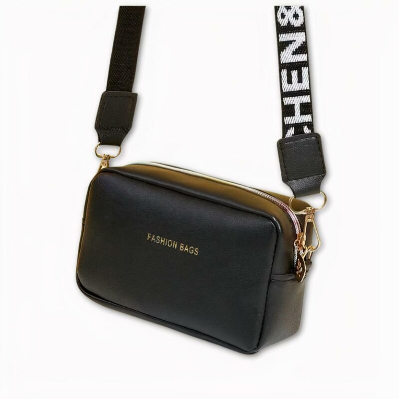 Photo d'une sacoche à bandoulière pour femme. De couleur noire, elle est suspendue par sa sangle noire avec des écritures blanches. Sa sangle est amovible et il y a d'écrit sur l'avant du sac "Fashion bags". Sa fermeture éclair et les mousquetons de la sangle sont de couleur dorée. Le fond de l'image est gris clair.