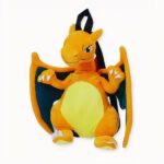 Une peluche pokemon dragon de couleur Jaune avec des ails sur un fond blanc cassé