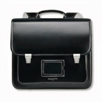 Cartable noir d'écolier traditionnel avec un porte carte devant, sur fond gris clair