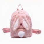 Sac à dos en peluche pour enfant de couleur rose avec des oreilles de lapin et une queue en pompon sur le devant.