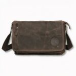 Cartable d'étudiant marron en toile avec bandoulière et une fermeture éclair sur le devant côté gauche, sur fond gris clair