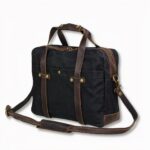 Cartable noir à bandoulière en toile cirée pour homme, sur fond gris clair