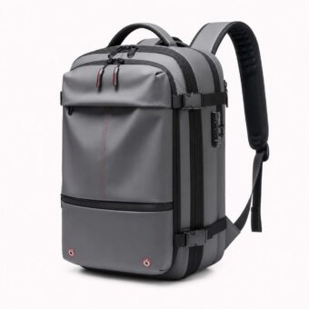 Un sac à dos voyage homme compression sous vide avec pompe gris, avec plusieurs fermetures éclair, des sangles de compression et une poignée sur le dessus, sur fond blanc.